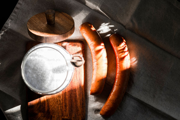 Sausages and milk jar on wooden board, morning light