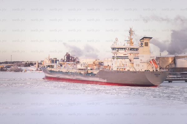 Cargo ship in icy harbor at sunrise