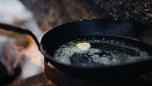 Melting butter in a cast iron pan over a campfire in the Luleå archipelago during winter