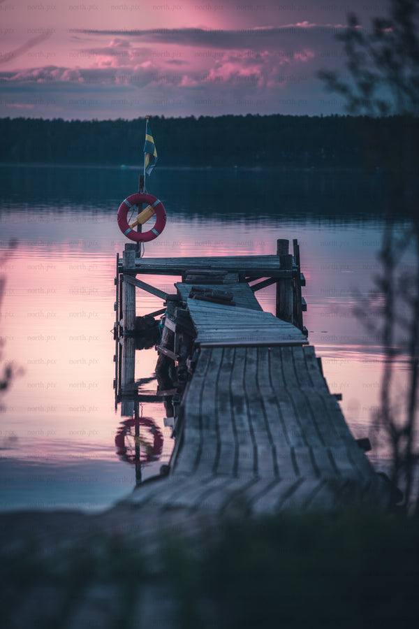 Wooden dock with lifebuoy and Swedish flag at dusk