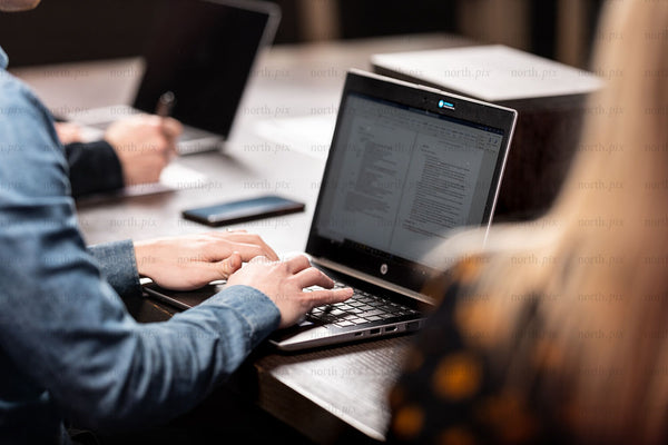 Person typing on laptop during office meeting