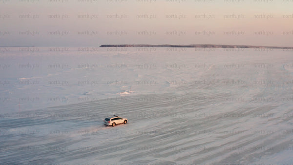 Driving on a frozen ice road in the Luleå archipelago at sunset
