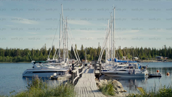 Summer day at Kluntarna archipelago: Sailboats and motorboats moored at wooden dock, Luleå