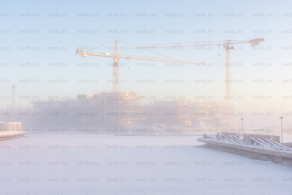 Construction cranes over frozen harbor in winter morning