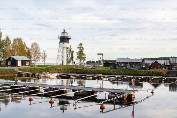 Lighthouse and marina with wooden boathouses in autumn