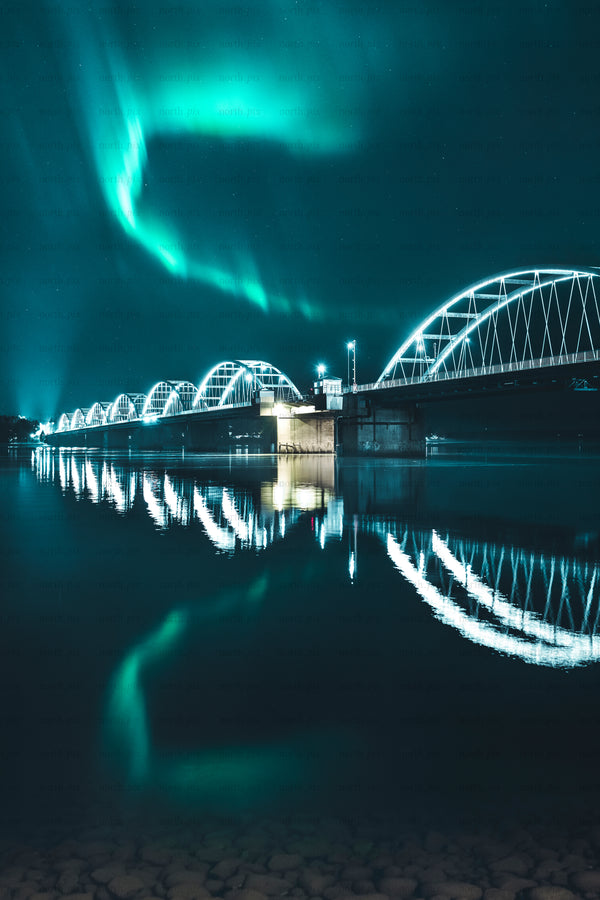 Northern Lights over arched bridge at night