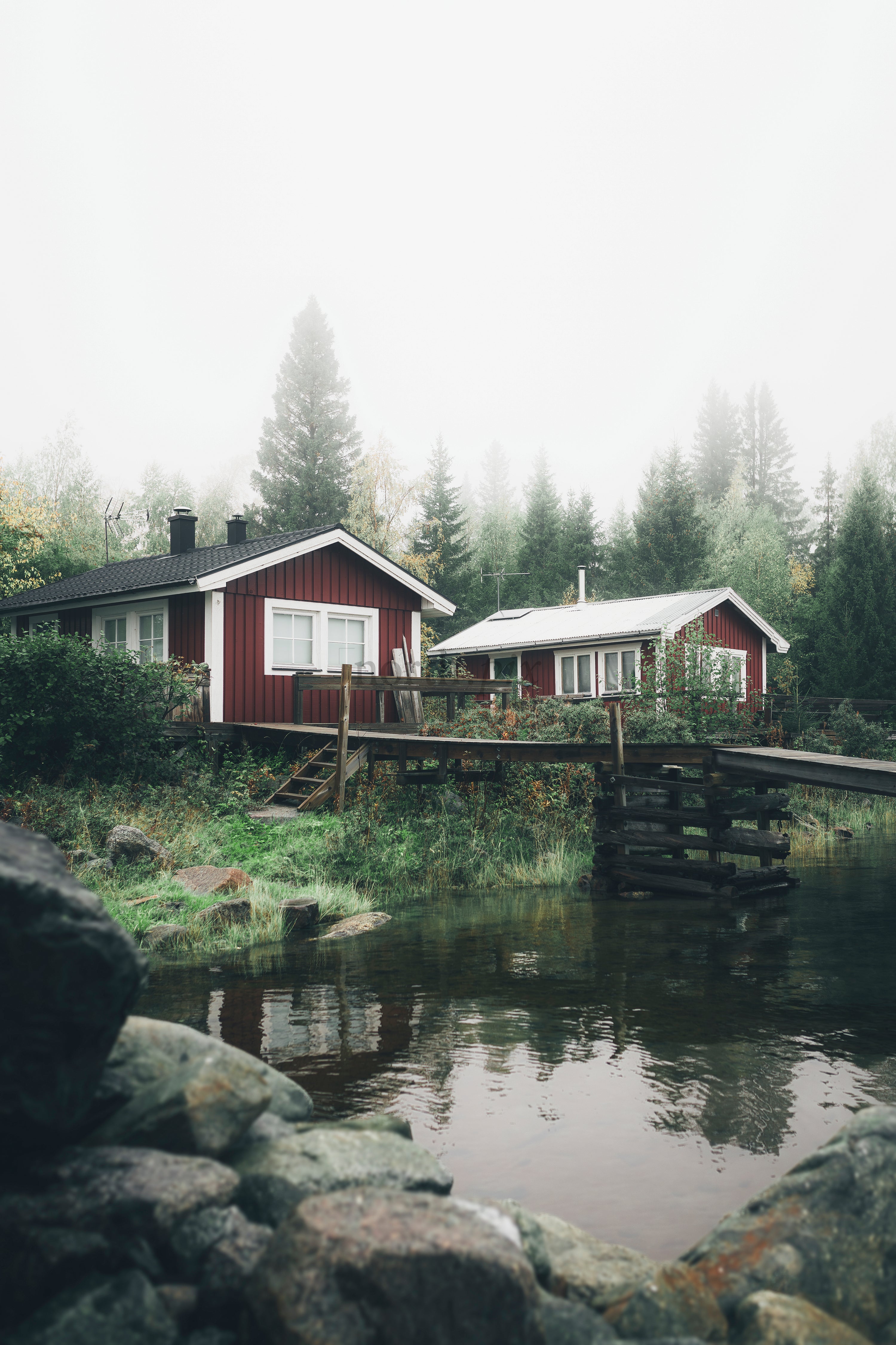 Red wooden cabins by lake with dock and forest