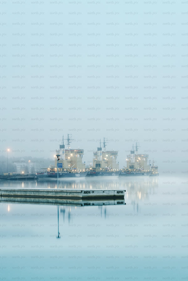 Three icebreakers docked at harbor in fog