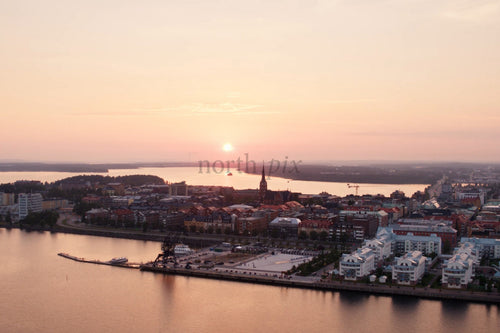 Solnedgång över Luleå centrum vid älvstranden med hamnkranar och moderna bostäder