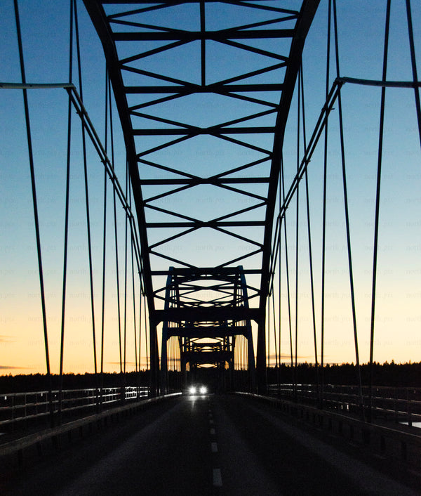 Steel arch bridge at dusk with car headlights