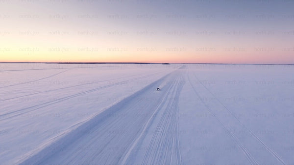 Driving on a frozen ice road in the Luleå archipelago at sunset during winter