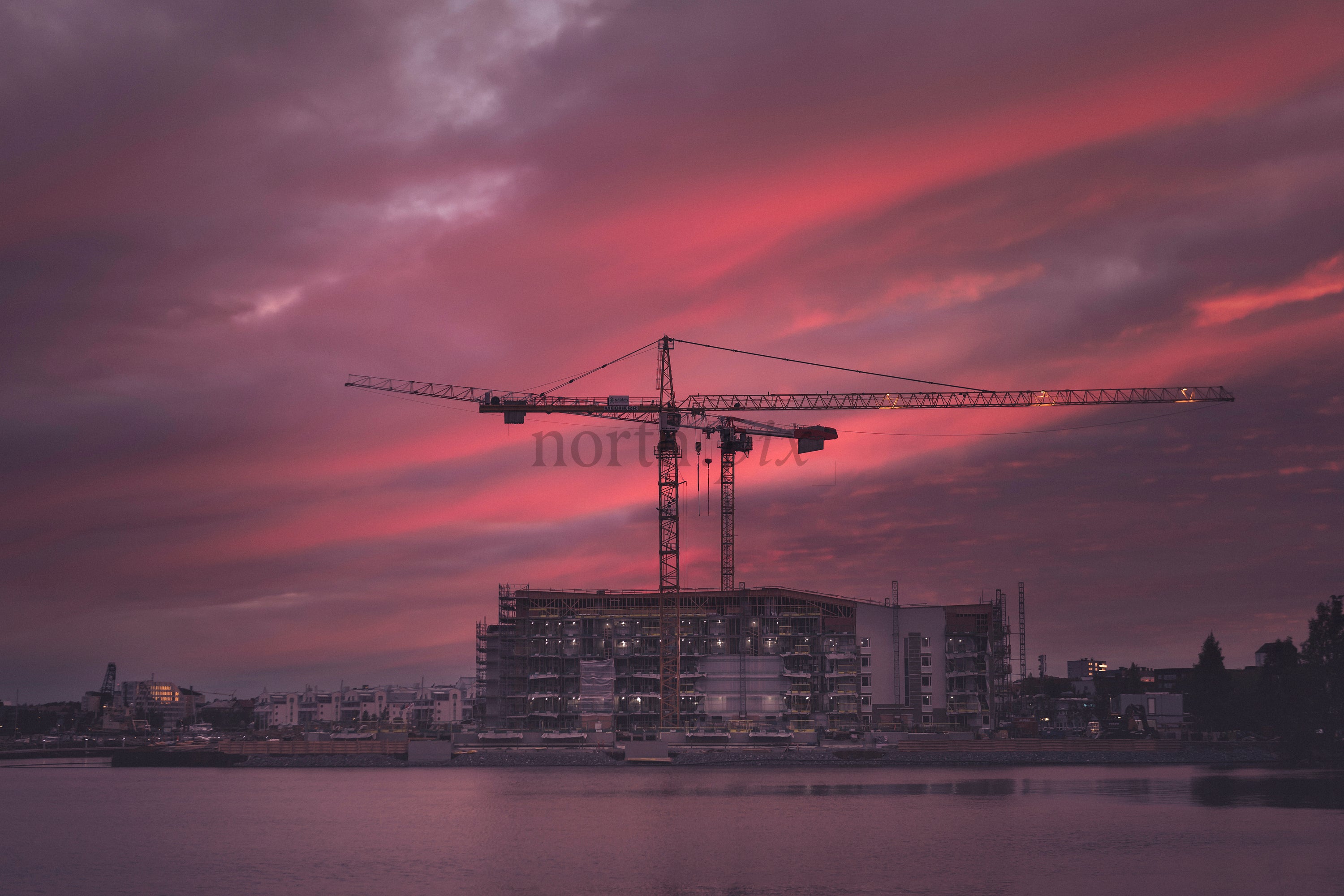 Construction cranes at waterfront during sunset