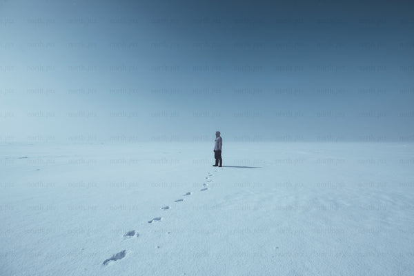 Person standing on a snowy plain under clear sky