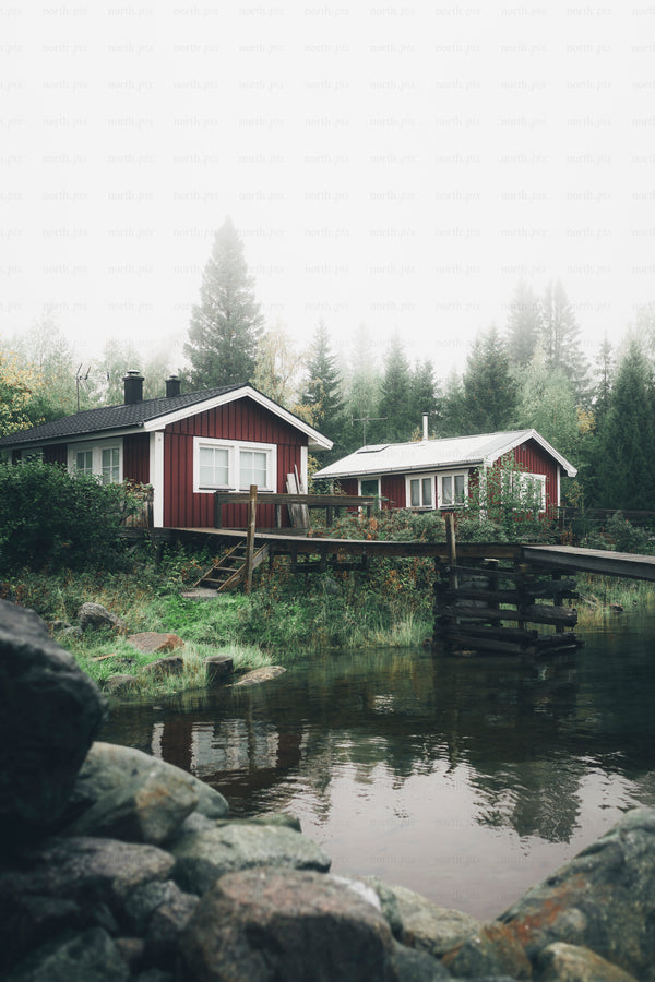 Red wooden cabins by lake with dock and forest