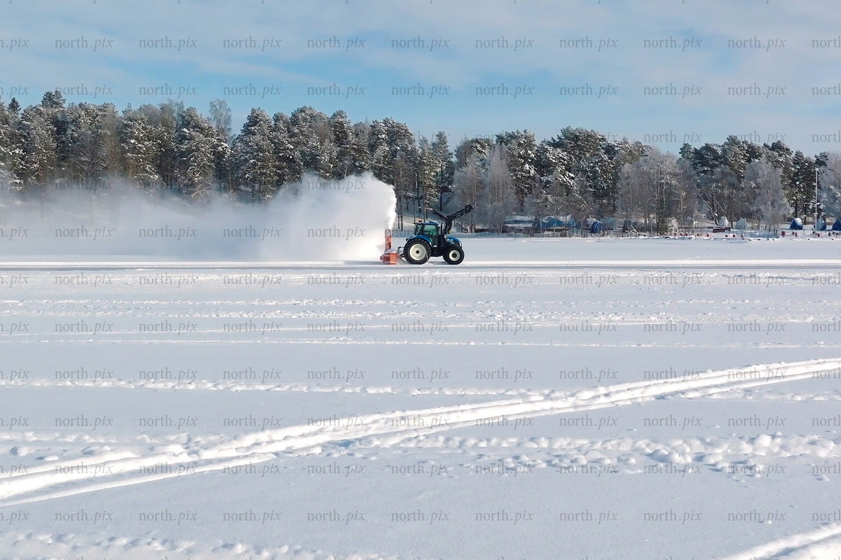 Vintersnöfält med traktor som röjer snö på frusen sjö nära Luleå centrum