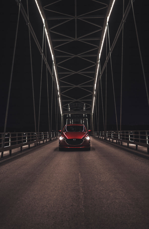 Red car on bridge at night