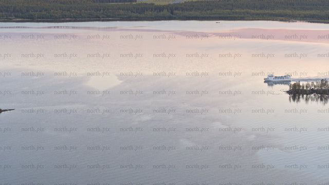 Luleå summer sunset: Ferry and boat on calm lake with scenic reflections