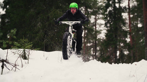 Man kör fatbike genom snötäckt skog i Luleå, Sverige, vinterdag