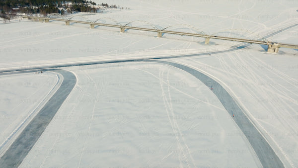 Aerial view of frozen river and bridge in Luleå, winter landscape with people