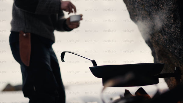 Man cooking on open fire on winter beach in Luleå archipelago