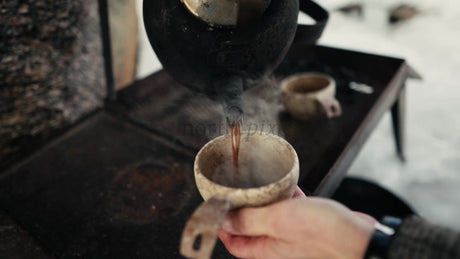 Pouring Hot Coffee into Kuksa in Winter Forest of Lulea, Sweden