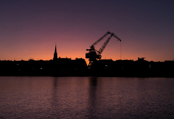 Harbor crane silhouette at sunset over water