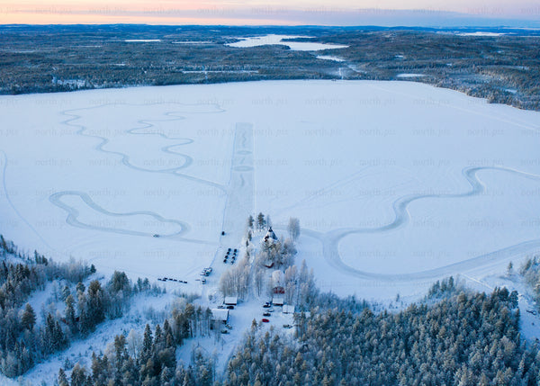 Aerial view of frozen lake and winter forest during sunrise