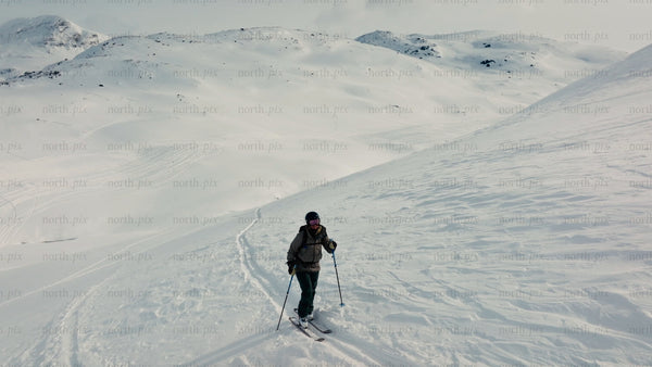 Skier ascends snowy mountain at riksgransen, Sweden, in winter