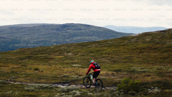 Man mountain biking down rocky terrain in scenic valley