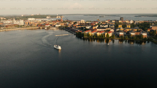 Aerial view of Luleå city on a summer evening: Boat tour, calm water, and sunset reflection