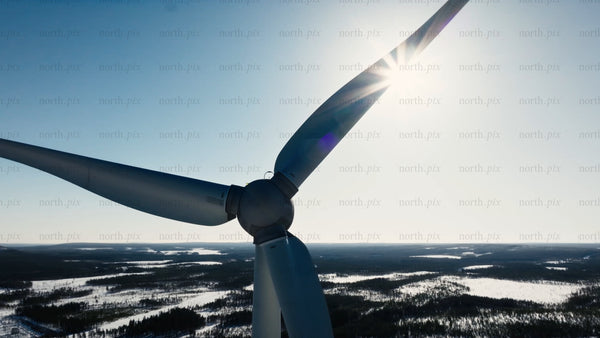 Rotating wind turbine at Markbygden wind farm in snowy Sweden during winter - drone aerial view