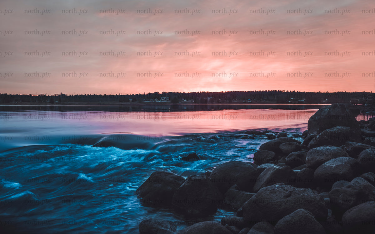 Klippor och strömmande vatten längs en solnedgångsstrand