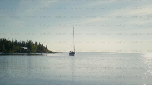Summer day in the Kluntarna archipelago: Sailboat moored near a lush island in Luleå