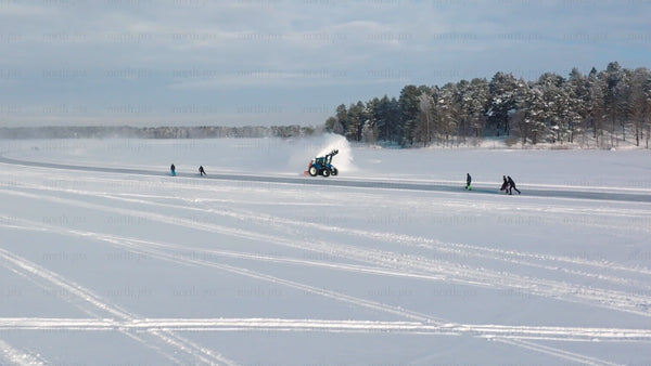 Tractor clearing snow on frozen lake in Luleå, with people skating and kick sledding