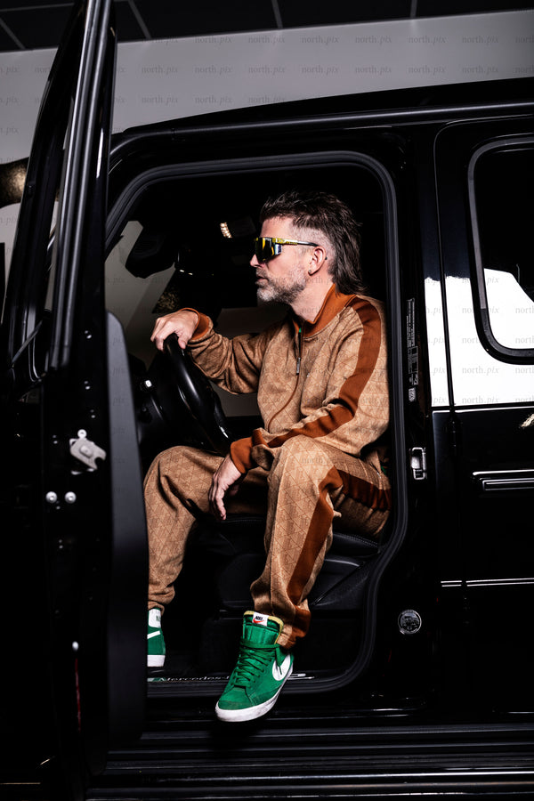 Man sitting in SUV wearing tracksuit and sunglasses