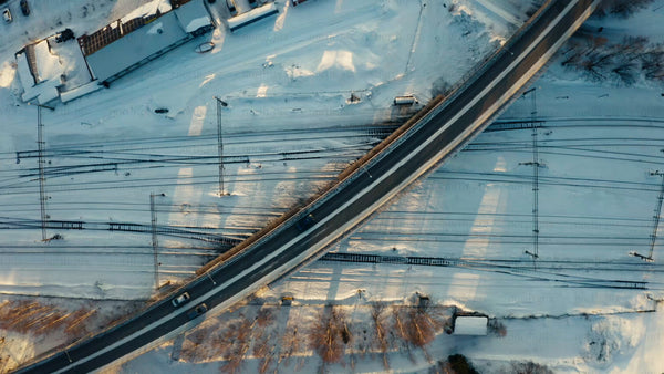 Aerial view of winter landscape: Car on bridge over railway in Luleå at sunset