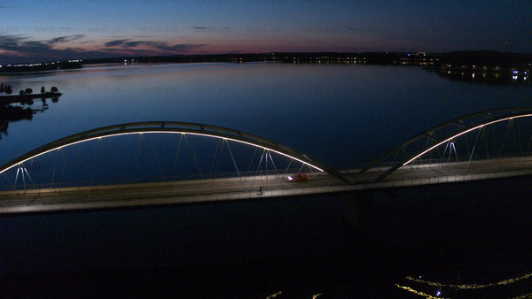 Aerial view of Luleå's Bergnäsbron bridge at twilight with city Lights and moon