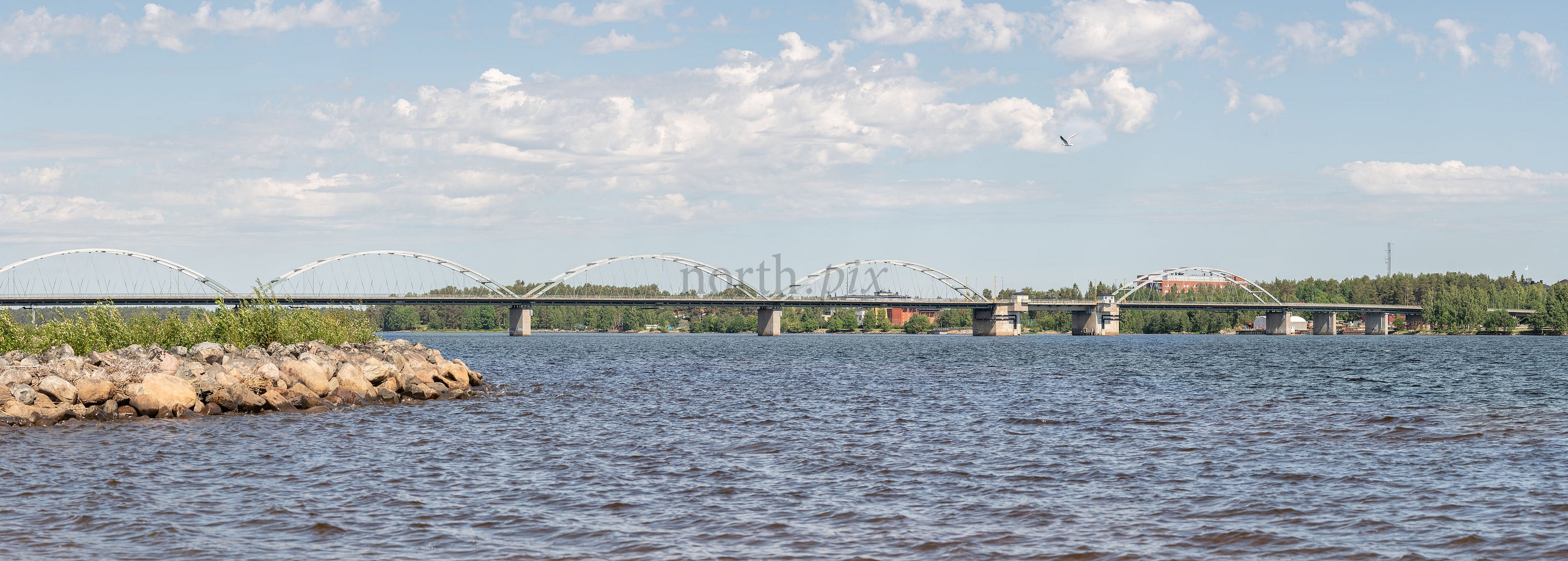 Panoramic view of arched bridge over river, summer afternoon