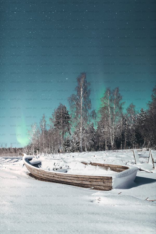 Wooden boat covered in snow under Aurora Borealis