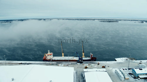 Flygfoto över ett lastfartyg förtöjt i Piteå Haraholmen hamn en kall vinterdag
