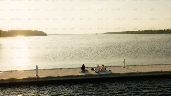 Friends enjoying sunset picnic on a pier in Luleå