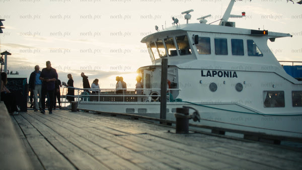 Urban summer evening: Passengers boarding tour boat at sunset in Luleå