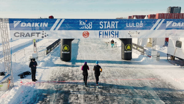 Runners crossing finish line at winter race on ice in Luleå