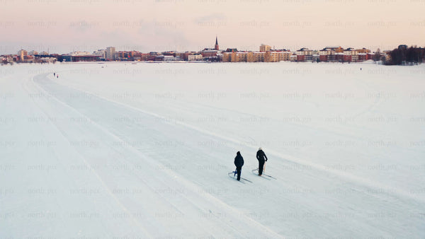 Winter sunset cross-country skiing on frozen lake in Luleå with city in background