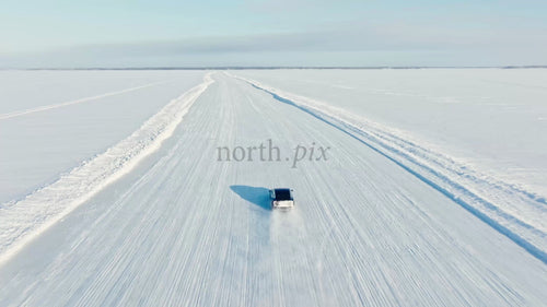 Vit Tesla/bil kör på snöig isväg i Luleå, Sverige, vinterdag, drönarbild