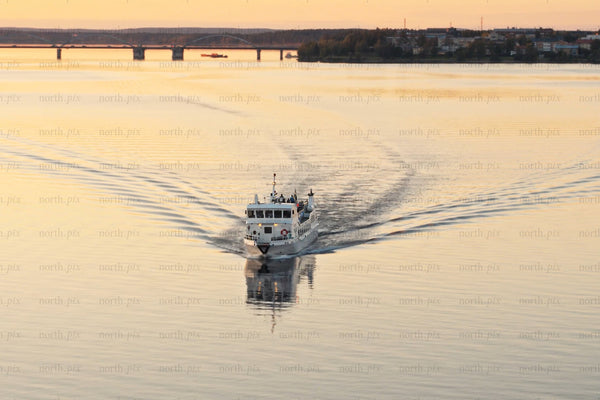 Sunset boat cruise over calm water near Luleå city center bridge and skyline