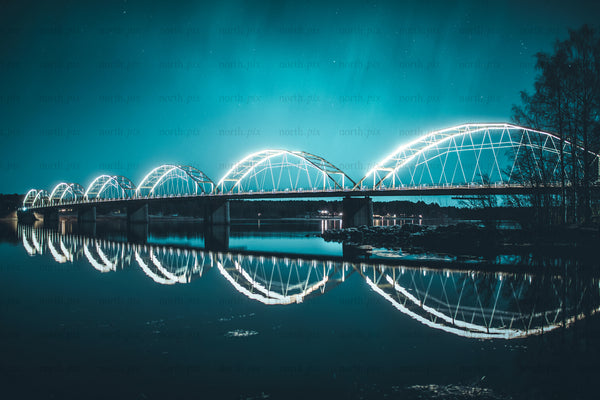 Illuminated arched bridge at night with reflections
