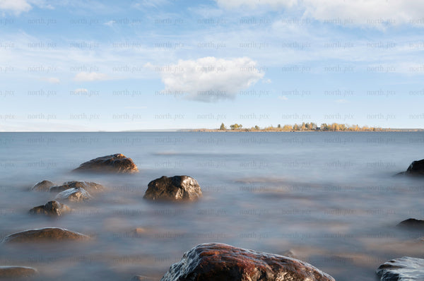 Rocks on lake shore with distant tree-covered island