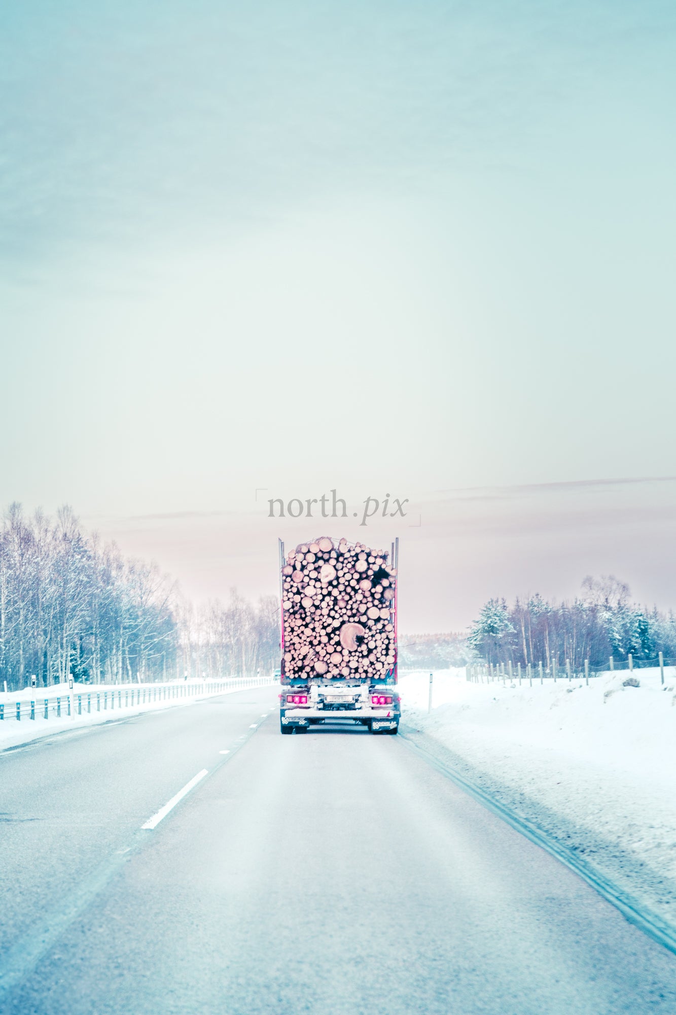 Log truck on snowy highway in winter morning