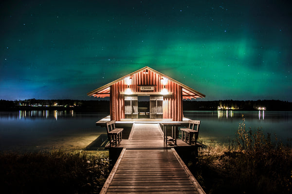 Wooden boathouse sjöbodan on lake dock under Aurora